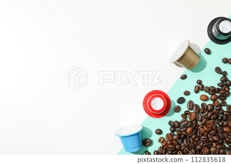 Colored coffee capsules and coffee beans on blue and white background, space for text 112835618