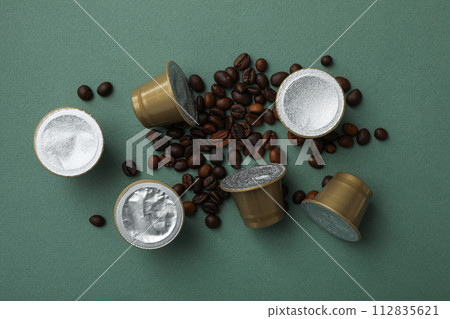 Coffee capsules and coffee beans on green background, top view Coffee capsules and coffee beans on green background, top view 112835621
