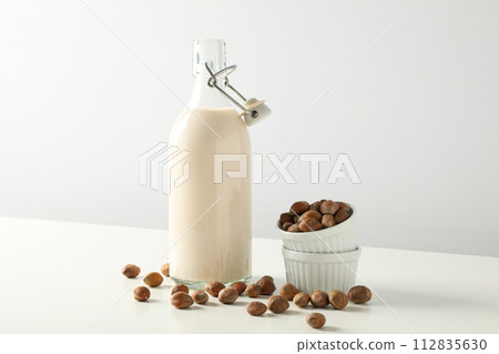 Bottle with milk and bowls with nuts on white background 112835630