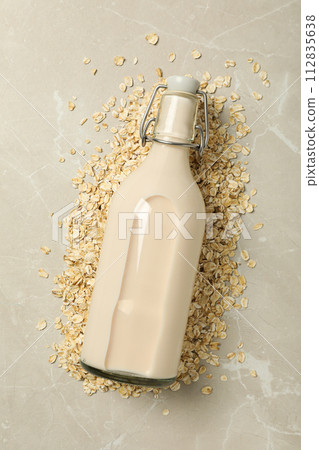 Bottle with milk and oatmeal on beige background, top view Bottle with milk and oatmeal on beige background, top view 112835638