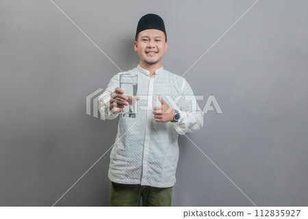 Happy asian muslim man holding glass of pure water give to camera Happy asian muslim man holding glass of pure water give to camera 112835927