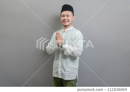 Asian Muslim man standing with Eid greeting gesture and welcoming Ramadan Asian Muslim man standing with Eid greeting gesture and welcoming Ramadan 112836004