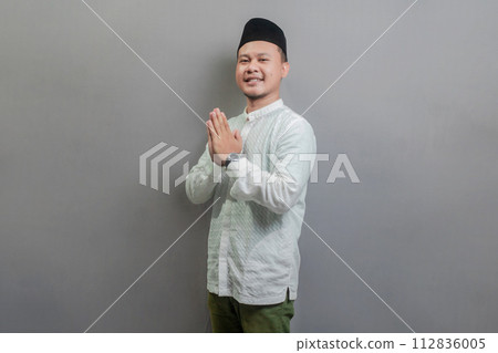 Asian Muslim man standing with Eid greeting gesture and welcoming Ramadan Asian Muslim man standing with Eid greeting gesture and welcoming Ramadan 112836005