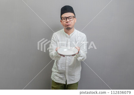 Asian Muslim man holding a plate while waiting for the time 112836079