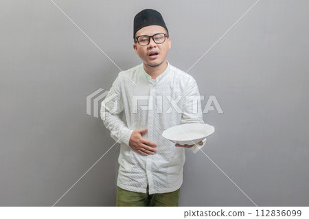Asian Muslim man holding back hunger and plate 112836099