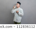 Happy asian muslim man drinking a fresh glass of pure water 112836112