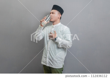 Happy asian muslim man drinking a fresh glass of pure water 112836112