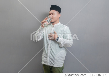 Happy asian muslim man drinking a fresh glass of pure water 112836113