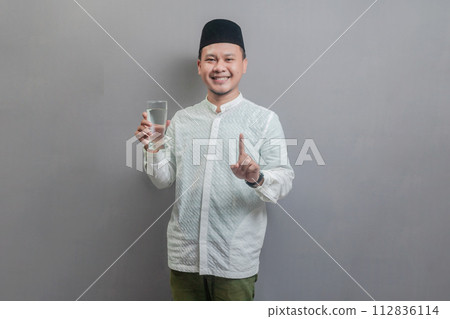 Happy asian muslim man holding glass of pure water give to camera 112836114
