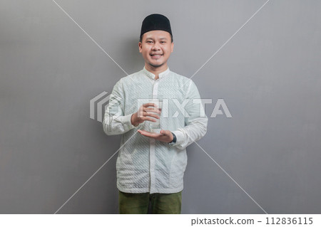 Happy asian muslim man holding glass of pure water give to camera 112836115