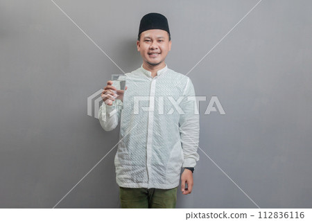 Happy asian muslim man holding glass of pure water give to camera 112836116