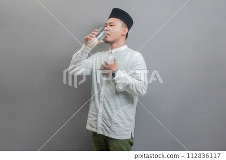 Happy asian muslim man drinking a fresh glass of pure water 112836117