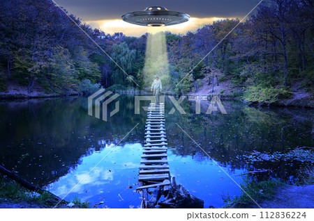 UFO hovered over a girl standing on the bridge of a mountain lake 112836224