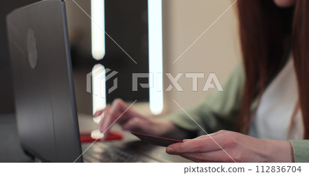 Close-up of young woman pressed the credit card code to pay online via the laptop. Commerce lifestyle concept, purchase transaction. Close-up of young woman pressed the credit card code to pay online via the laptop. Commerce lifestyle concept, purchase transaction. 112836704
