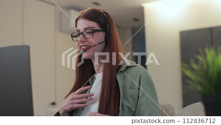 Young woman sitting at home wear wireless headset having video conference. Concept of remote work or education. 112836712