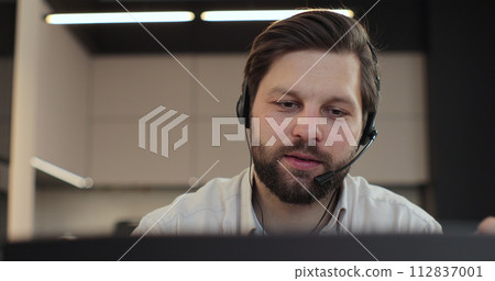 Closeup face man wearing headset and talking, call center worker. Positive young man wearing headset. Phone assistance service concept. Closeup face man wearing headset and talking, call center worker. Positive young man wearing headset. Phone assistance service concept. 112837001