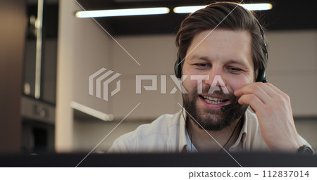 Closeup face man wearing headset and talking, call center worker. Positive young man wearing headset. Phone assistance service concept. Closeup face man wearing headset and talking, call center worker. Positive young man wearing headset. Phone assistance service concept. 112837014