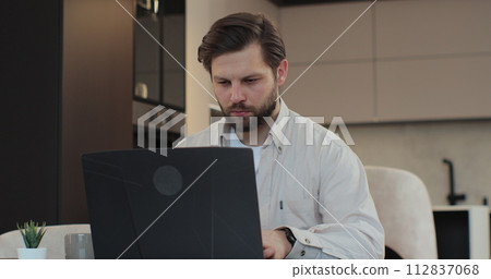 Man at home kitchen distant work with laptop. Working from home, online shopping, watching video. Technology and people concept. Man at home kitchen distant work with laptop. Working from home, online shopping, watching video. Technology and people concept. 112837068