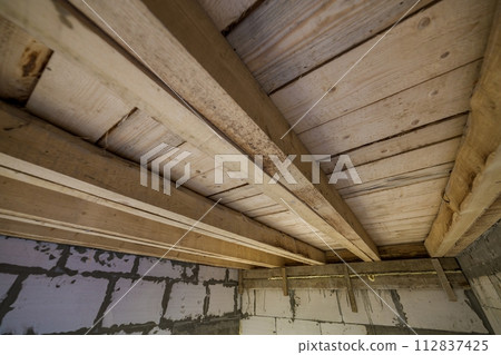 Close-up detail of house room interior under construction and renovation. Energy saving walls of hollow foam insulation blocks, wooden ceiling beams for roof frame. 112837425