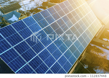 Close-up surface of lit by sun blue shiny solar photo voltaic panels system on building roof. Renewable ecological green energy production concept. 112837448