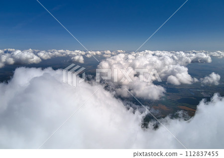 Aerial view from airplane window at high altitude of earth covered with puffy cumulus clouds forming before rainstorm. Aerial view from airplane window at high altitude of earth covered with puffy cumulus clouds forming before rainstorm. 112837455