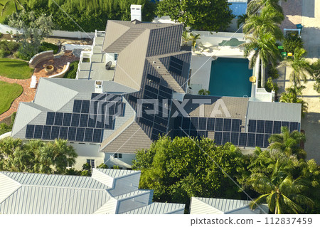 Big new residential house in USA with rooftop covered with solar photovoltaic panels for producing of clean ecological electrical energy in suburban rural area. Concept of autonomous home Big new residential house in USA with rooftop covered with solar photovoltaic panels for producing of clean ecological electrical energy in suburban rural area. Concept of autonomous home 112837459