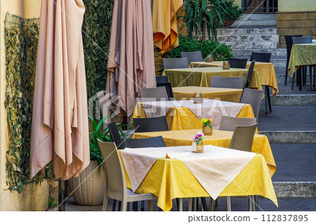 Outdoor restaurant seating area with empty chairs and tables in Agrigento, Italy. 112837895