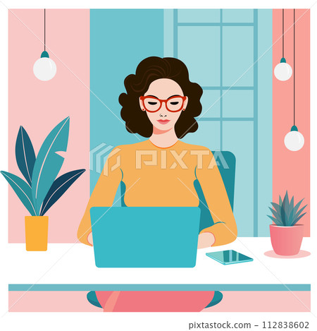 A young woman sits at a desk in a modern office, working on a laptop 112838602