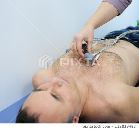 Heart cardiogram in the hands of a doctor close-up. Cardiologist is studying the testimony of electrocardiograph. 112839488
