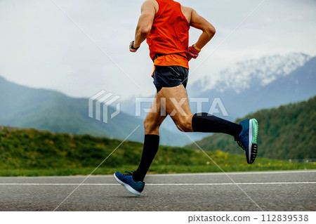 male athlete running mountain marathon on asphalt in black compression socks 112839538