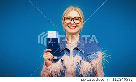 A senior woman is showing her passport and airplane ticket, an active lifestyle and travel plans A senior woman is showing her passport and airplane ticket, an active lifestyle and travel plans 112840582