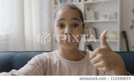 African American teenager creating content, talking to subscribers online, showing like gesture on camera African American teenager creating content, talking to subscribers online, showing like gesture on camera 112840655