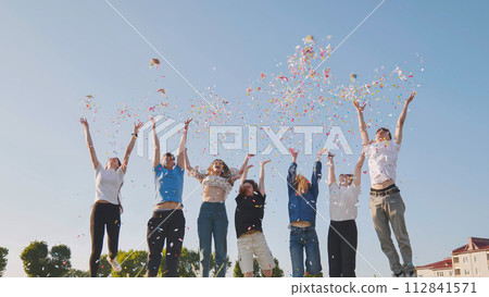 Friends toss colorful paper confetti from their hands. 112841571
