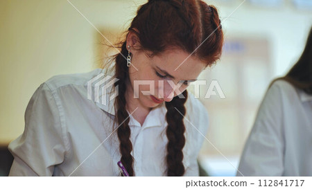 High school girls at a desk in the classroom during class. High school girls at a desk in the classroom during class. 112841717