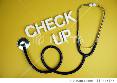 Stethoscope and Check up alphabet letters top view on yellow background Stethoscope and Check up alphabet letters top view on yellow background 112843177