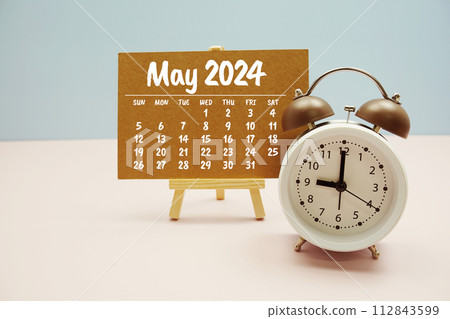 May 2024 monthly calendar on easel stand with alarm clock on pastel background May 2024 monthly calendar on easel stand with alarm clock on pastel background 112843599