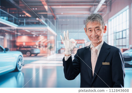 一名男子在汽車經銷店為顧客服務 一名男子在汽車經銷店為顧客服務 112843608