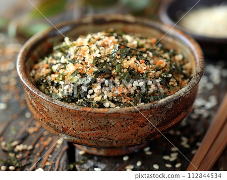 Furikake is a Japanese seasoning made from a mixture of dried and ground ingredients in bowl 112844534