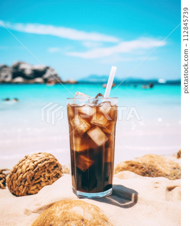 Plastic take away glass with iced coffee against background of landscape with blue sea, refreshing summer go-to drink with ice 112845739