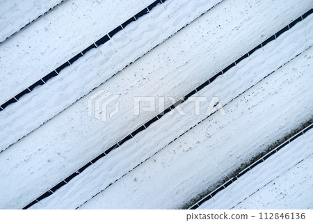 Aerial view of snow covered sustainable electric power plant with rows of solar photovoltaic panels for producing clean electrical energy. Low effectivity of renewable electricity in northern winter 112846136