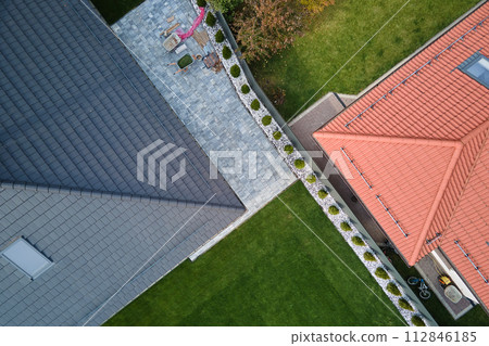 Closeup of house roof top covered with ceramic shingles. Tiled covering of building 112846185