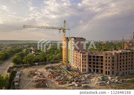 Aerial view of building site. Apartment or office building under construction. Tower cranes on suburb landscape and blue sky copy space background. 112846188