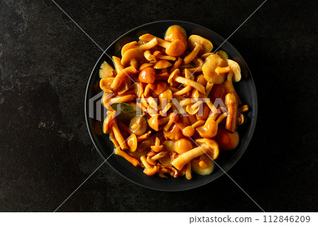 Homemade pickled honey mushrooms  on a black stone table. 112846209