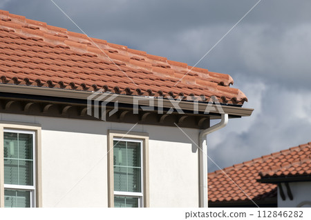 Tiled roof covering of condo building in Florida. Closeup of house rooftop covered with ceramic shingles 112846282