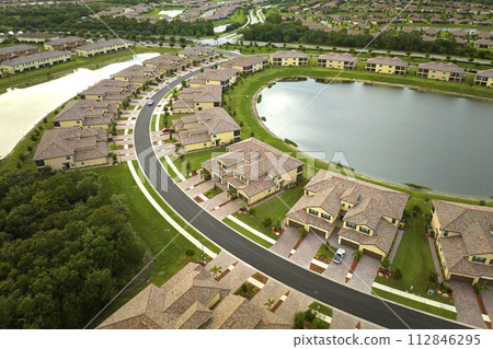 Aerial view of tightly packed homes in Florida closed living clubs with lake water in the middle. Family houses as example of real estate development in american suburbs 112846295