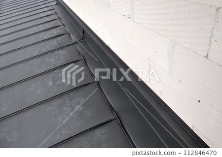 Close-up detail of house roof made from gray metal sheets. 112846470