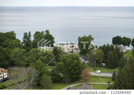 Two-story residential waterfront houses on lake Ontario shore in rural living area in Rochester, NY. American dream homes as example of real estate development in US suburbs 112846480