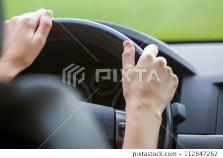 Woman hands on steering wheel driving a car. 112847262
