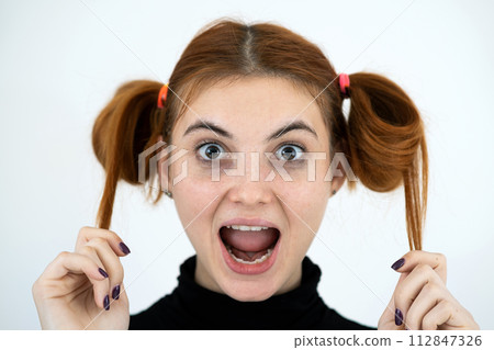 Closeup portrait of a funny redhead teenage girl with childish hairstyle smiling happily isolated on white backround. 112847326