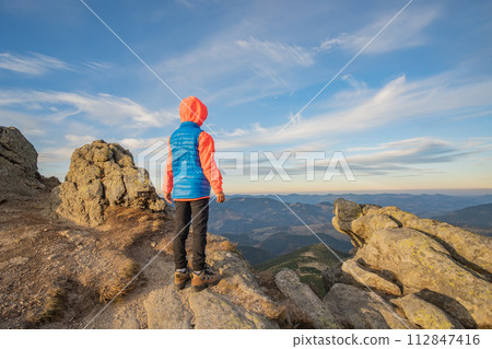 Young child boy hiker standing in mountains enjoying view of amazing mountain landscape. Young child boy hiker standing in mountains enjoying view of amazing mountain landscape. 112847416